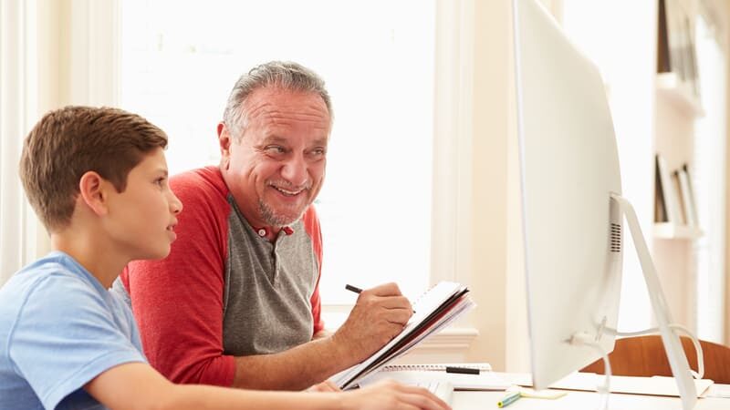 Granddad and grandson working on a computer, perhaps for a Jumble Puzzles