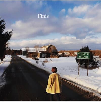 A woman walking down a rural, snow-lined road entering Freeville with the words "Finis" in the sky. To Ask Amy readers: Amy Dickinson is ending her 21-year-old column.