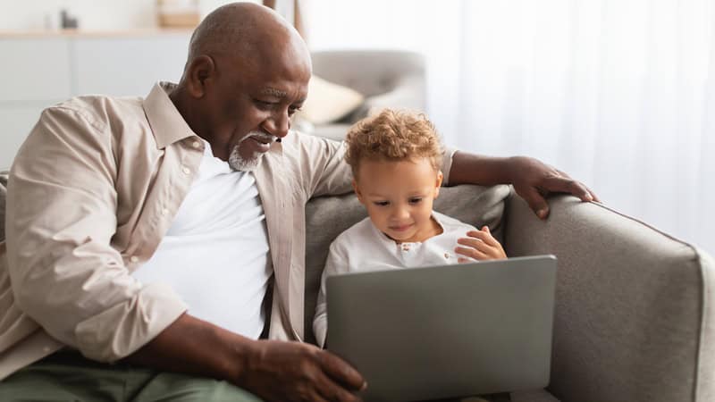 a granddad and his grandchild looking at a laptop, possibly doing puzzles online Prostockstudio