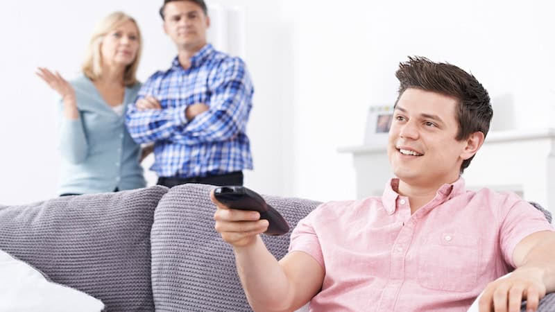 An exasperated mother and father look on as their young adult son uses the TV remote. Article on When the Kids Move Back Home. There may come a time when adult children need to be treated like roommates or tenants, rather than kids.