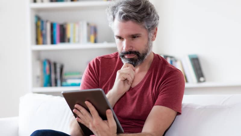 Middle-age man staring intently at a tablet. By Kadettmann. Boggle BrainBusters: Country Search