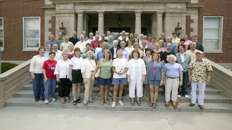 A 40th high school reunion, by Joe Sohm. Old classmates pose for a photograph on the steps of their school.