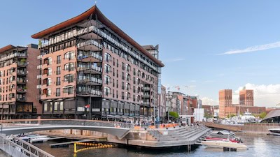 Aker Brygge, Oslo's former shipyard, is today home to a mix of high-end condos, restaurants, and shopping. Oslo City Hall, with its twin towers, sits at the head of the harbor. (Cameron Hewitt, Rick Steves' Europe)