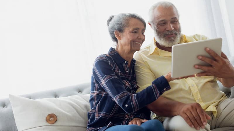 A couple on their sofa looking at a computer tablet, perhaps doing a puzzle like the Boggle the birds word search puzzle