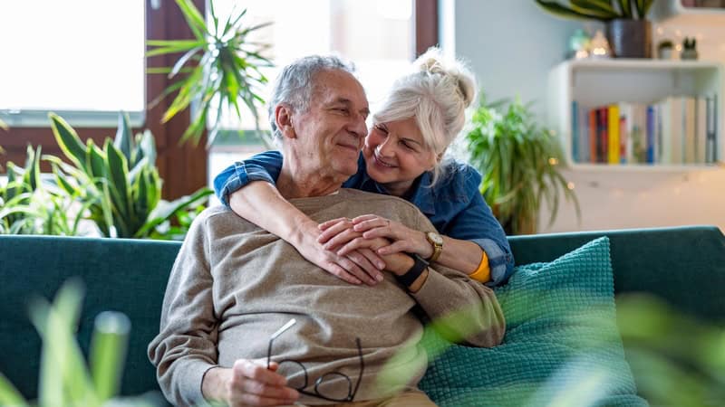 A happy, affectionate senior couple at home. Image by Piksel. Used with advice column on sharing a dark past.