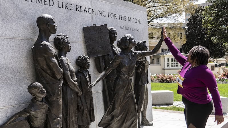 A passerby high-fiving Barbara John at the Civil Rights memorial on the grounds of the Richmond capitol, Virginia. For More What's Booming RVA: September 19 to 26