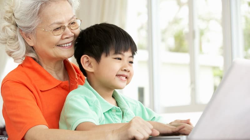 a grandma and grandson on a laptop, smiling, perhaps even playing the Jumble puzzles with Blackbeard and a scaly thief