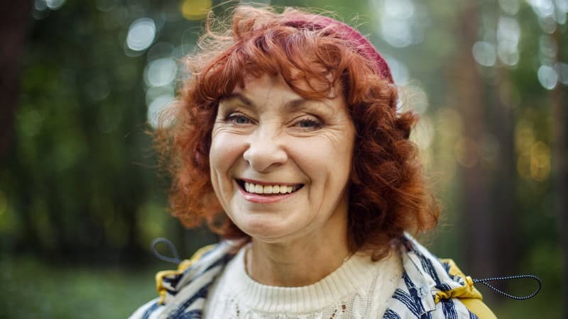 A happy red-headed woman outside, happy after rethinking her outlook on aging