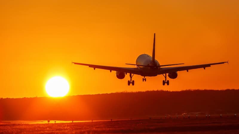 Airplane taking off, heading into the sunset. For article on Avoiding Three Airline Add-On Fees