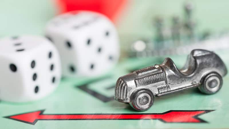 Dice and classic car game piece on a Monopoly board. Image by Kmiragaya. Used with humor essay on Monopoly Baby Boomer edition.