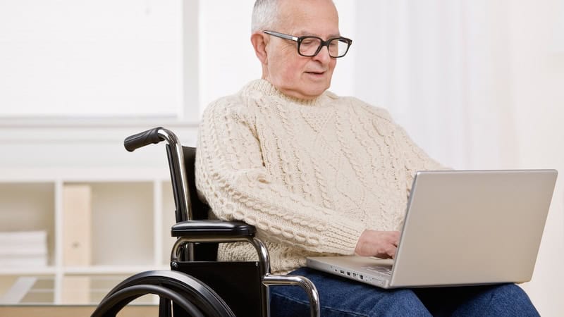 man in a wheelchair on a laptop, perhaps doing puzzles like the Boggle Mammal Version word search