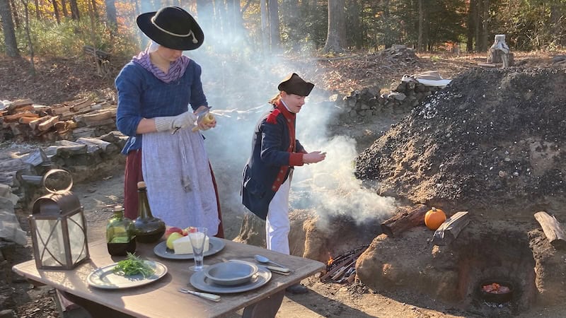 Foods and Feasts - woman and man in colonial garb cooking outside