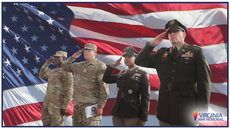 Four military service members saluting with an American flag in the background. From the Virginia War Memorial