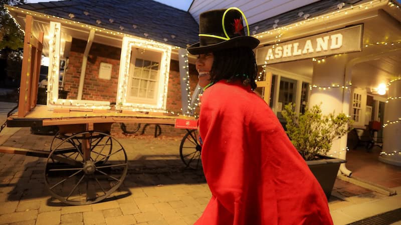 Ashland train station lit for the holiday season, with a Christmas-dressed woman. For What's Booming, November 21