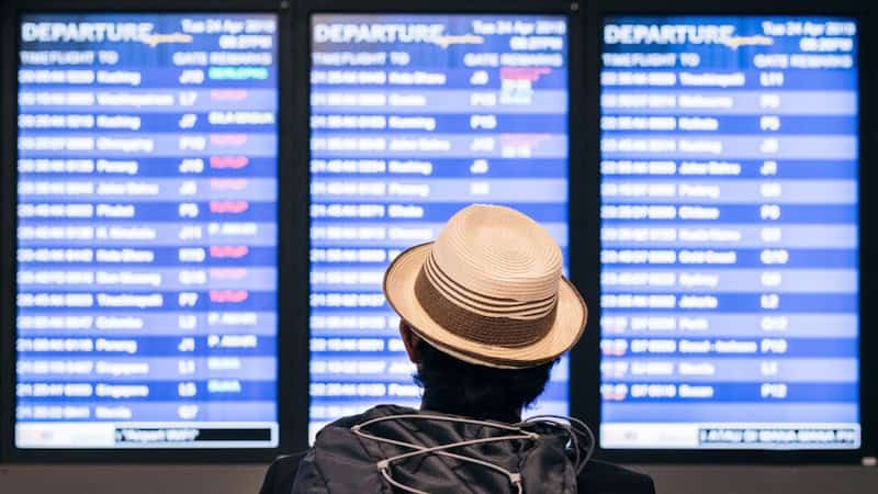 Person looking up at an airport flight schedule timetable, used on article with new airline rules that took effect Oct. 28, 2024