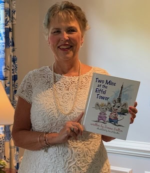 Author Donna Dalton of the Two Mice books hold up a copy of the first book, Two Mice at the Eiffel Tower 