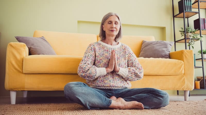 Easing in to meditation: a woman meditating in her living room. Image by Roman Samborskyi