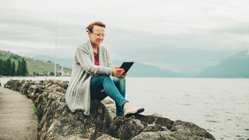 Woman using her tablet beside a lake on a chilly fall day. Used with Boggle search for animals puzzle