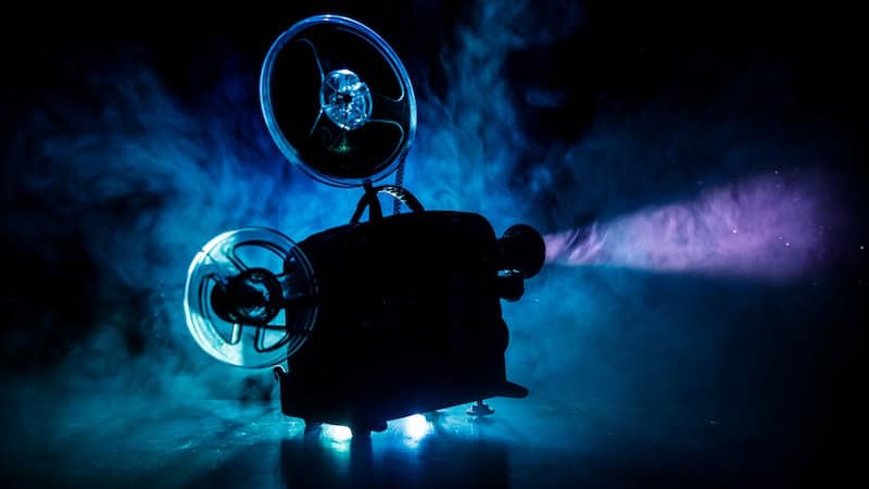 An antique projector used to make what's now old movies - projecting a light into a smoky-blue room. By Ilkin Guliyet