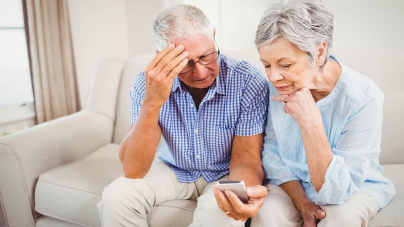 puzzled couple looking at smartphone. on daughter-in-law has begun restricting grandparents’ contacts with her kids – their grandkids. by wavebreak media