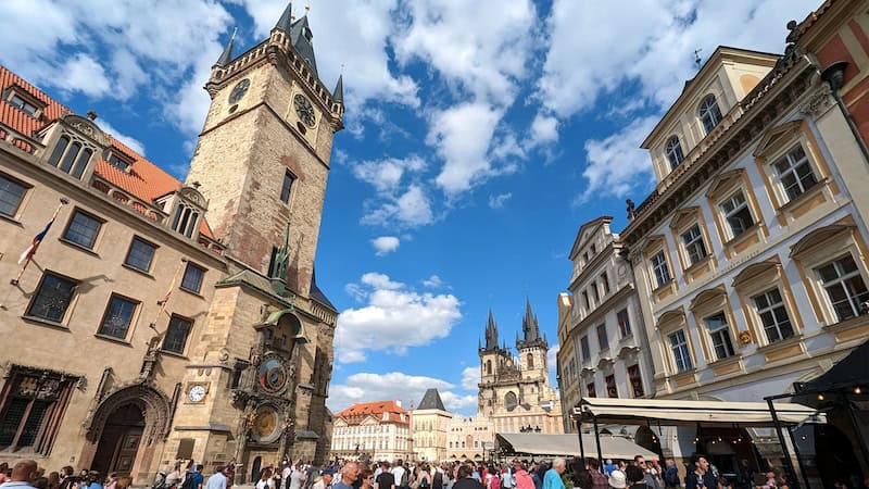 On Prague’s Old Town Square, a medieval astronomical clock intrigues visitors; the spiky Týn Church towers in the background. Part of what you can see on a stroll through Prague. CREDIT: (Glenn Eriksen, Rick Steves’ Europe)