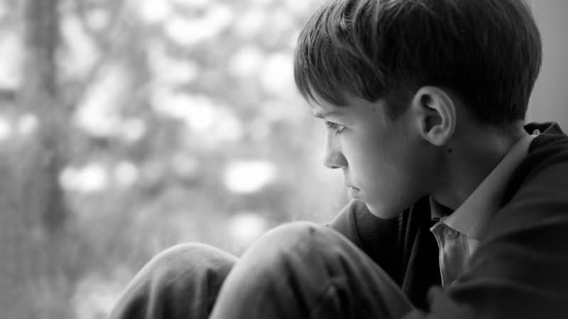 Thoughtful young man looking out of a window, part of growing up. Image by Rimma Zaytseva